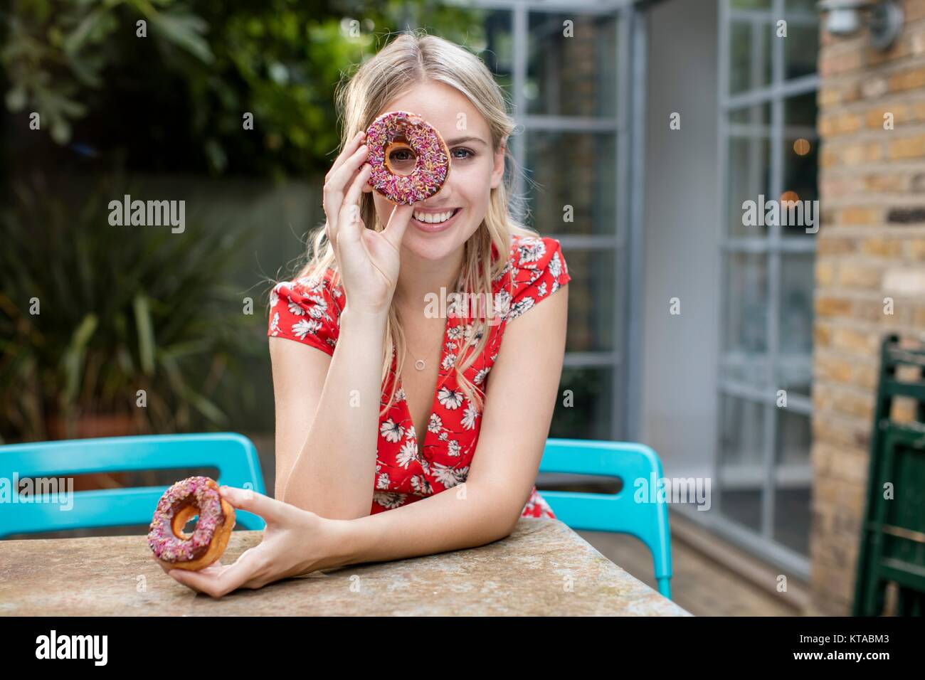 Junge Frau mit Donut für Auge. Stockfoto