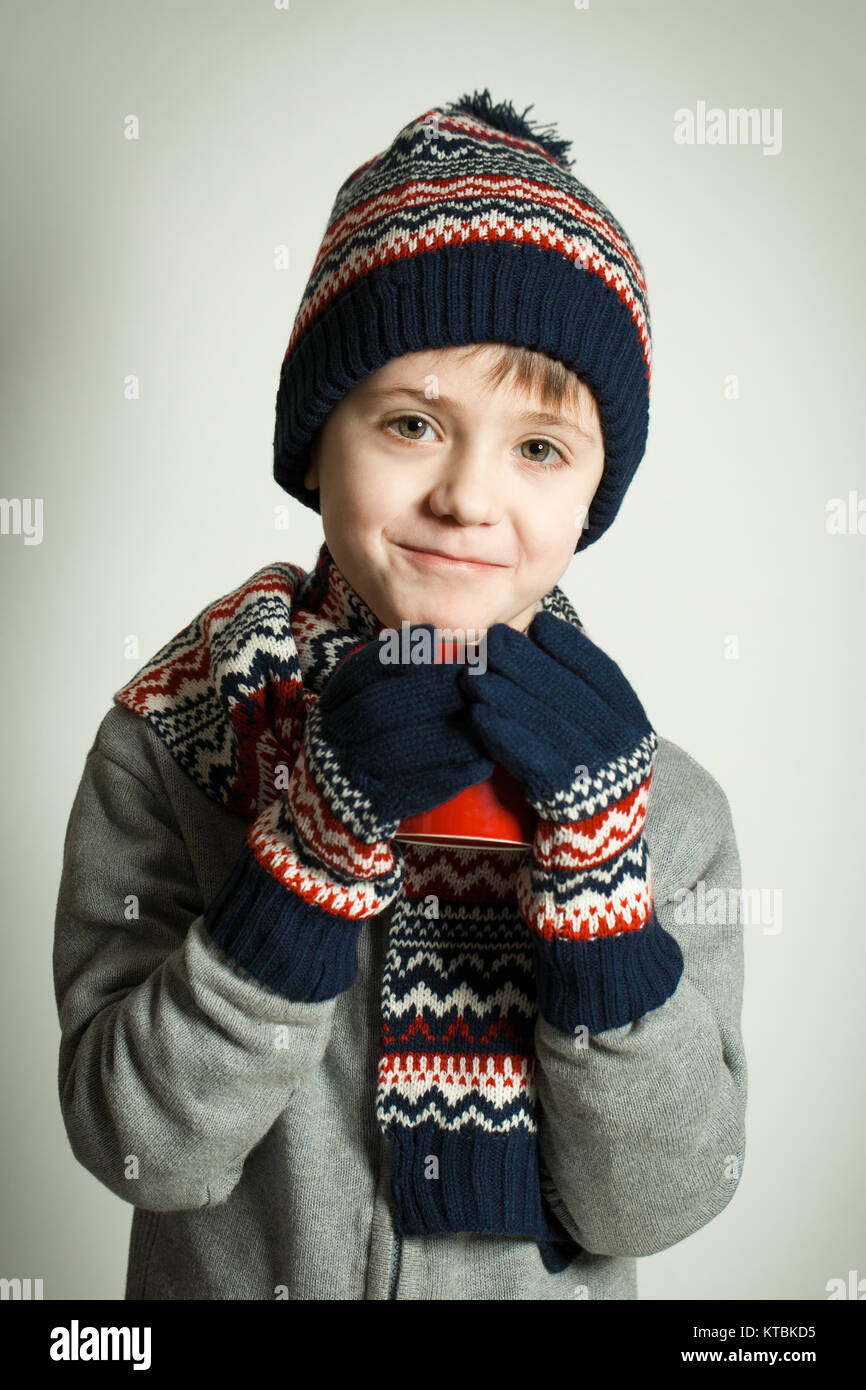 Glückliches Kind trägt eine Wollmütze und Schal, trinken heissen Tee Stockfoto