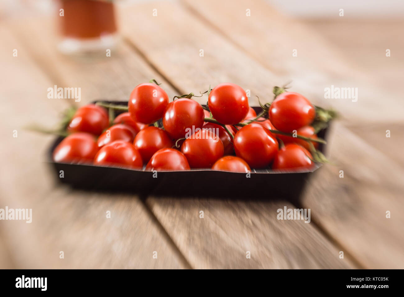 Kleine Rispentomaten in einer Schale auf einem Holzbrett Stockfoto