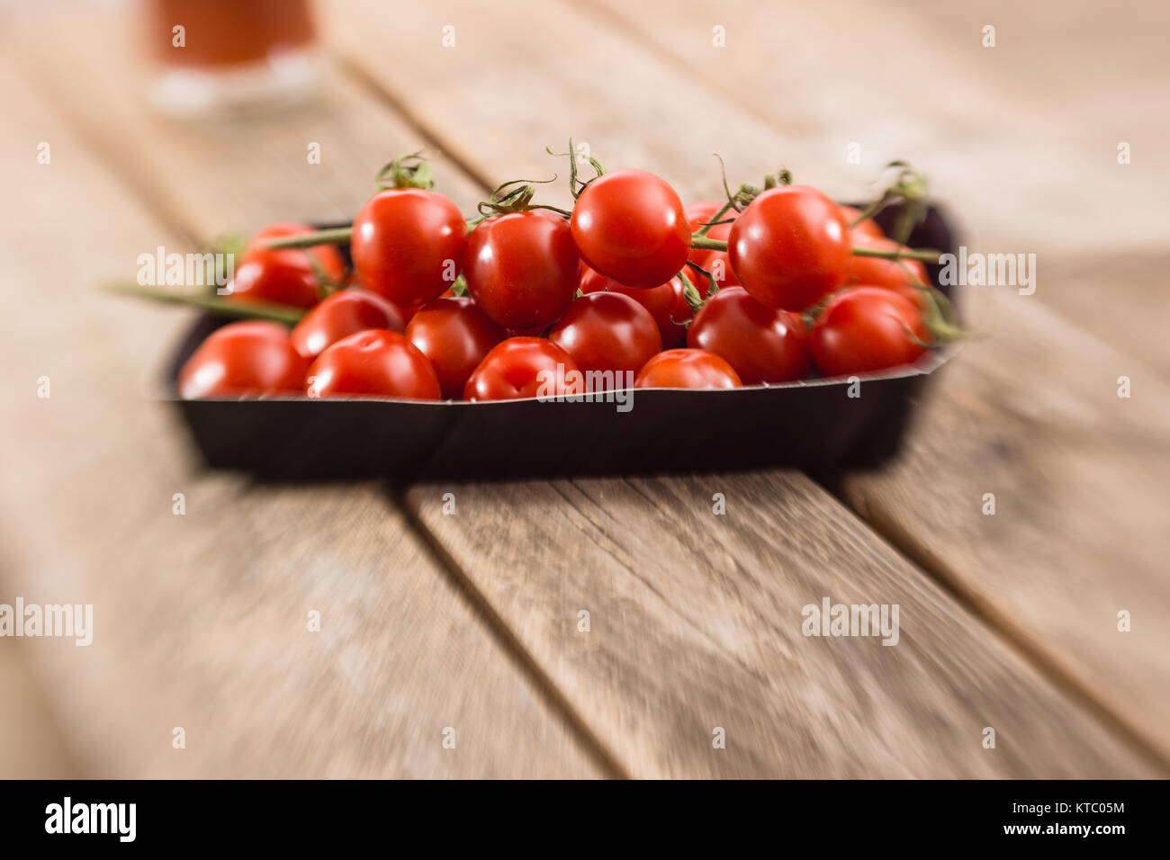 Kleine Rispentomaten in einer Schale auf einem Holzbrett Stockfoto