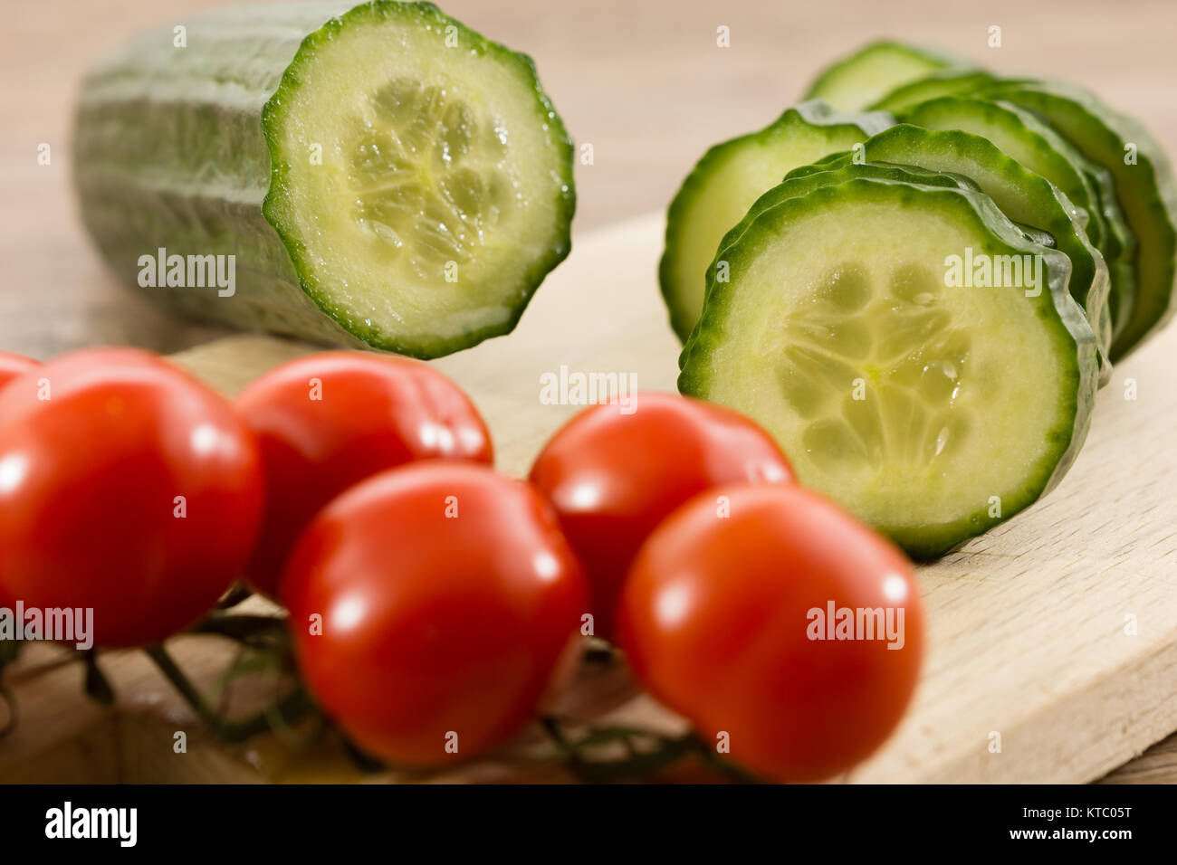 Eine geschnittene Salatgurke und Rispentomaten Stockfoto