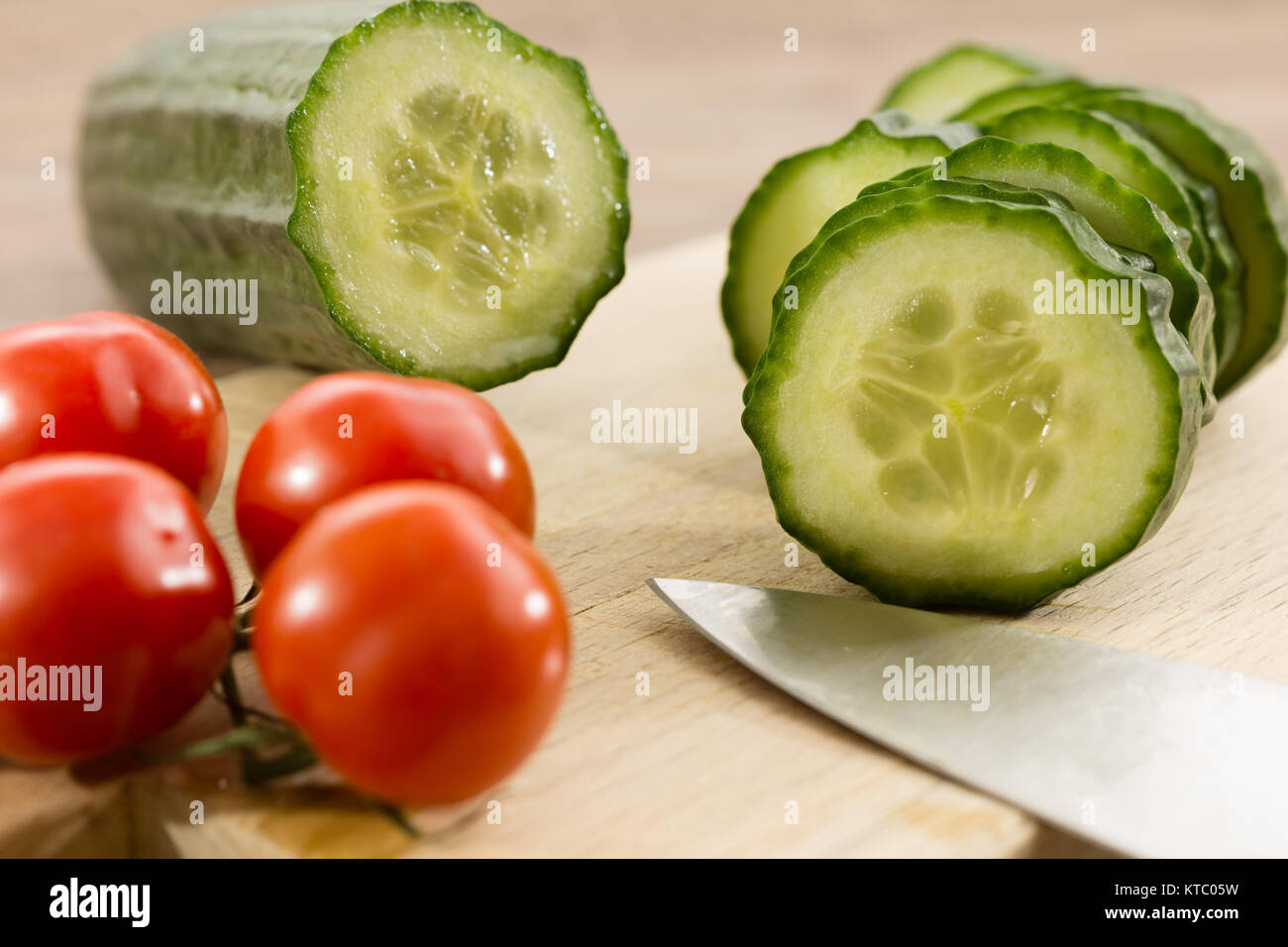 Eine geschnittene Salatgurke und Rispentomaten Stockfoto