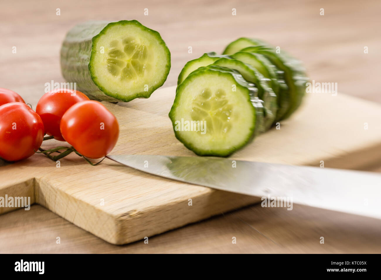 Eine geschnittene Salatgurke und Rispentomaten Stockfoto