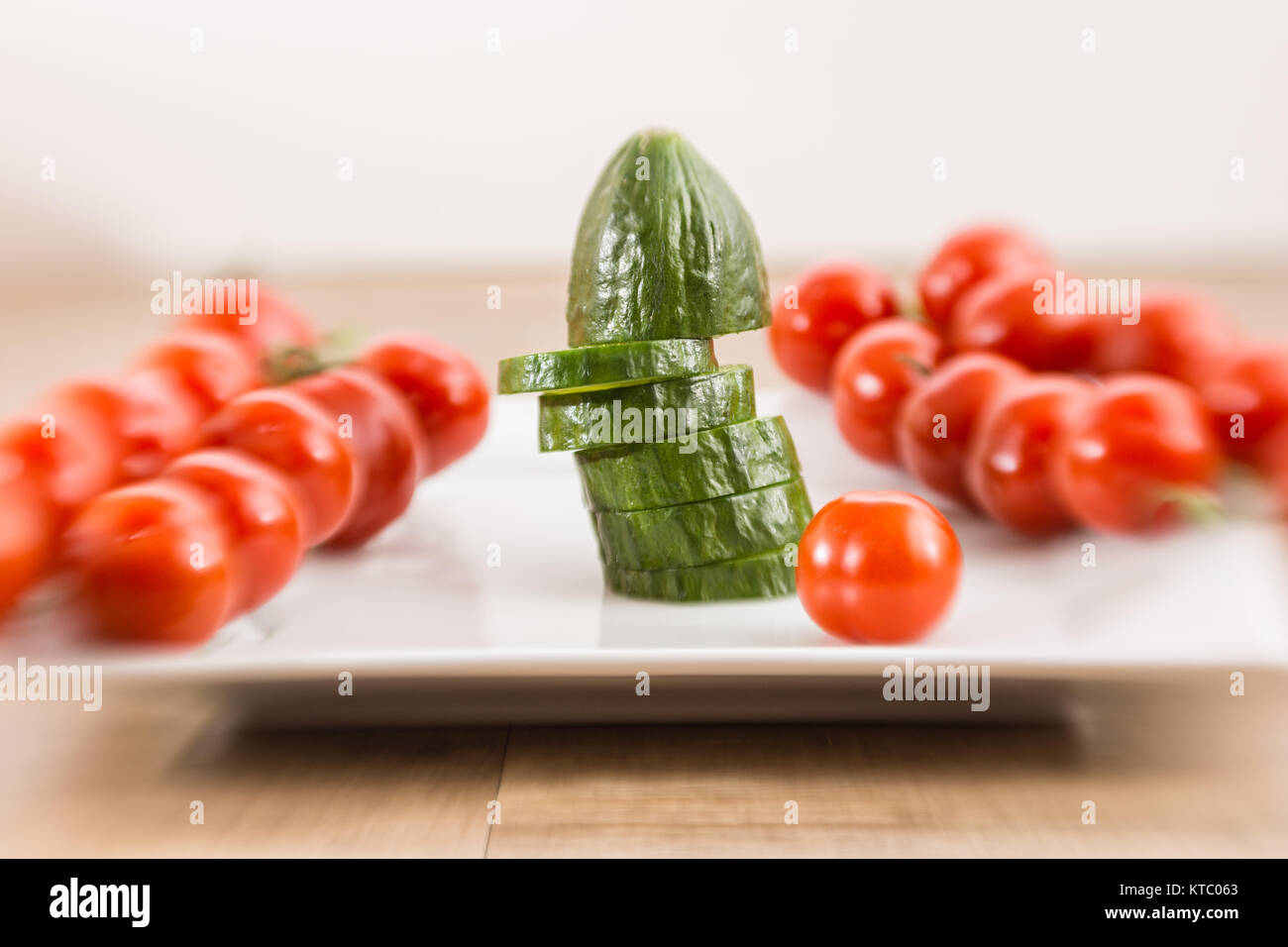 Eine geschnittene Salatgurke und Rispentomaten auf einem Teller Stockfoto