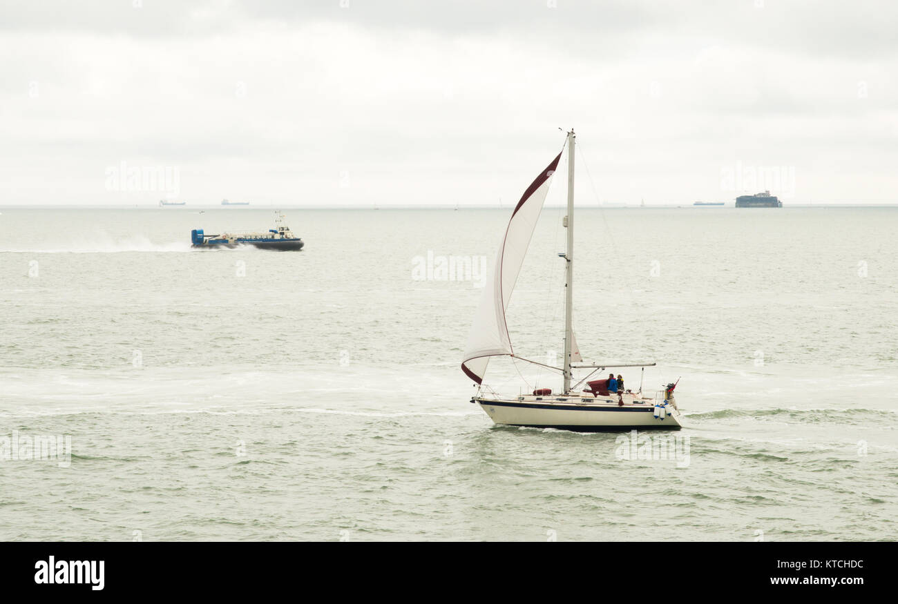 Eine Yacht segeln durch den Solent mit einem hovercraft in der Ferne. Stockfoto