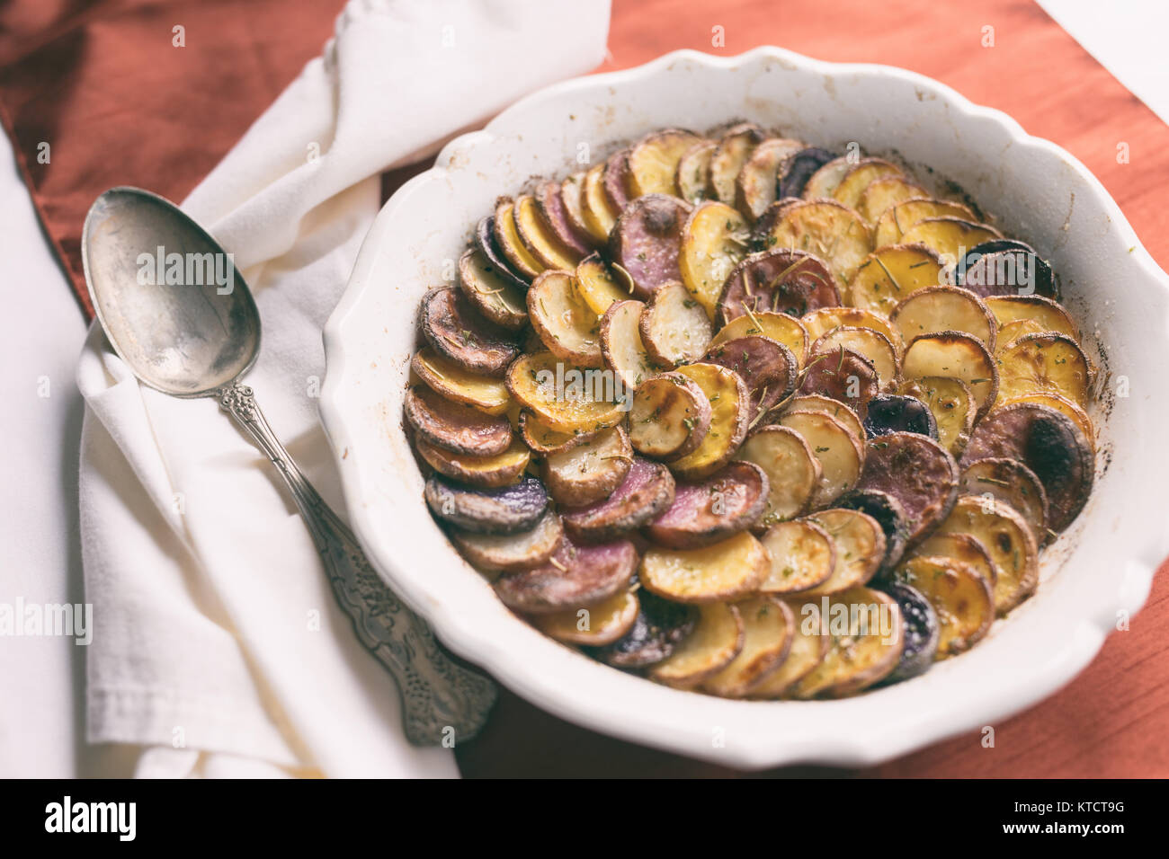 Weißen flachen Teller mit dünn geschnittenen Kartoffeln gefüllt. Mit Kräuterkruste und gegrillt. Stockfoto