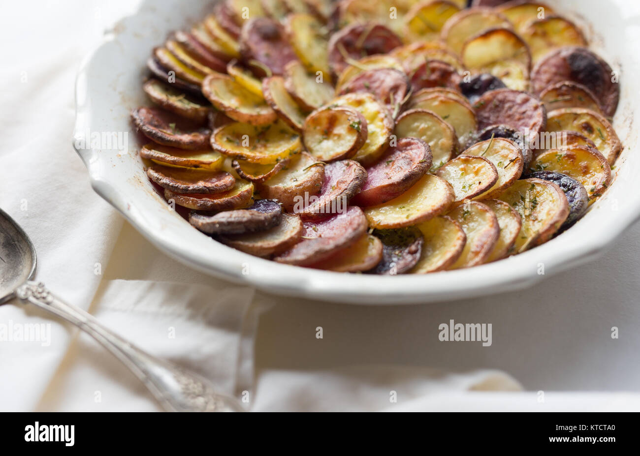 Weißen flachen Teller mit dünn geschnittenen Kartoffeln gefüllt. Mit Kräuterkruste und gegrillt. Stockfoto
