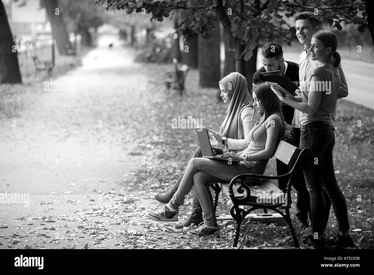 Gruppe von Jugendlichen mit Notebook und Tablet-PC auf einer Parkbank, Spass haben, Reden, heraus hängen Stockfoto