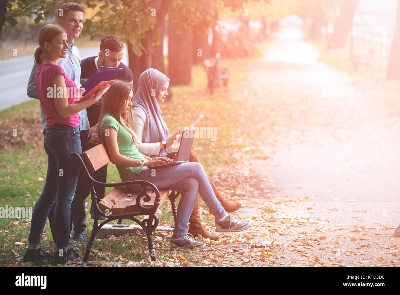 Gruppe von Jugendlichen mit Notebook und Tablet-PC auf einer Parkbank, Spass haben, Reden, heraus hängen Stockfoto