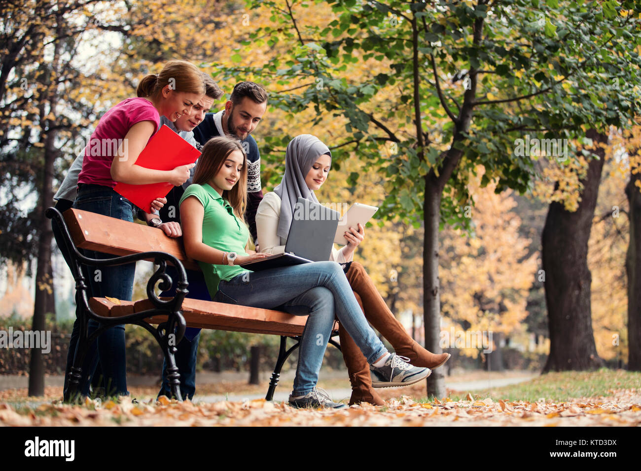Gruppe von Jugendlichen mit Notebook und Tablet-PC auf einer Parkbank, Spass haben, Reden, heraus hängen Stockfoto