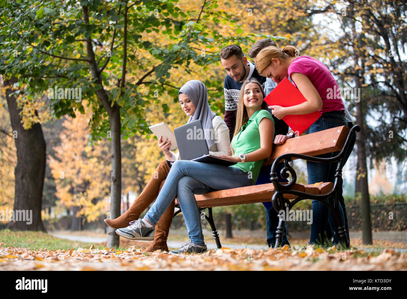 Gruppe von Jugendlichen mit Notebook und Tablet-PC auf einer Parkbank, Spass haben, Reden, heraus hängen Stockfoto