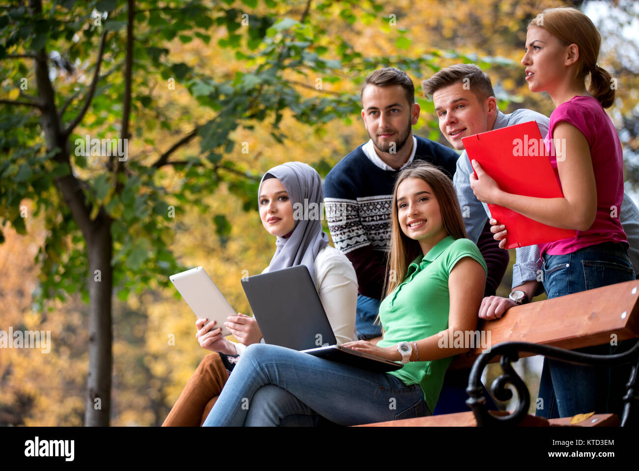 Gruppe von Jugendlichen mit Notebook und Tablet-PC auf einer Parkbank, Spass haben, Reden, heraus hängen Stockfoto