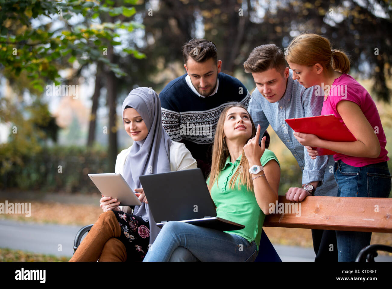 Gruppe von Jugendlichen mit Notebook und Tablet-PC auf einer Parkbank, Spass haben, Reden, heraus hängen Stockfoto