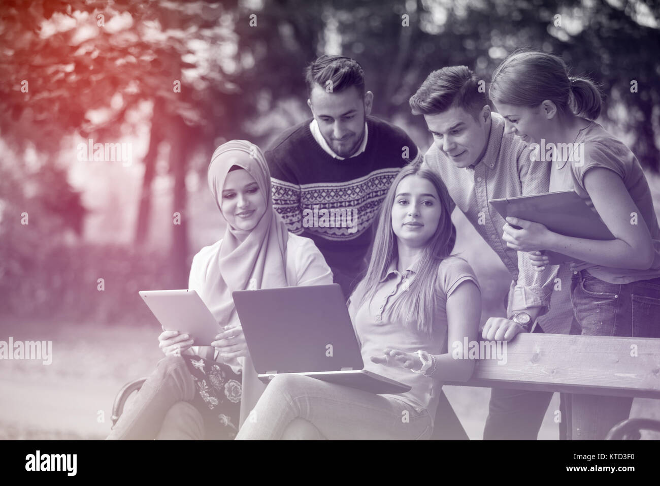 Gruppe von Jugendlichen mit Notebook und Tablet-PC auf einer Parkbank, Spass haben, Reden, heraus hängen Stockfoto