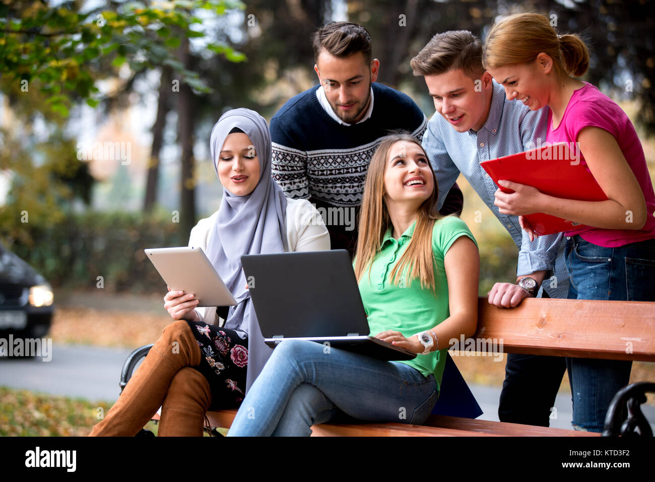 Gruppe von Jugendlichen mit Notebook und Tablet-PC auf einer Parkbank, Spass haben, Reden, heraus hängen Stockfoto