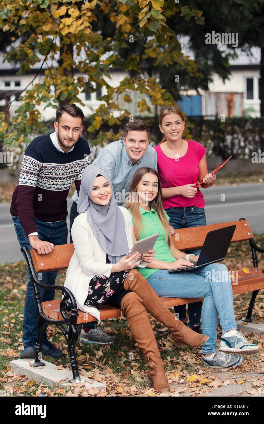 Gruppe von Jugendlichen mit Notebook und Tablet-PC auf einer Parkbank, Spass haben, Reden, heraus hängen Stockfoto