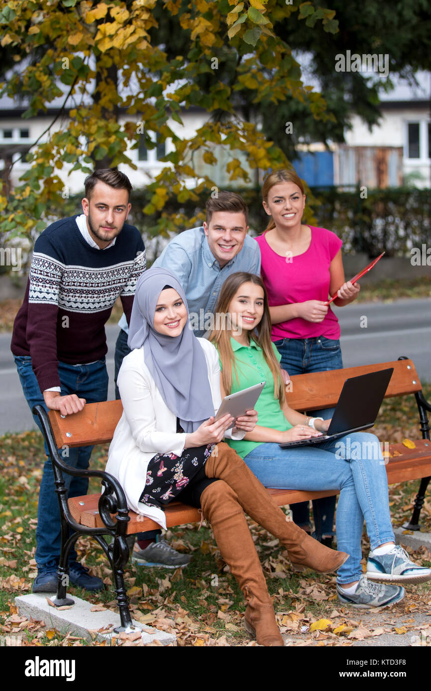 Gruppe von Jugendlichen mit Notebook und Tablet-PC auf einer Parkbank, Spass haben, Reden, heraus hängen Stockfoto