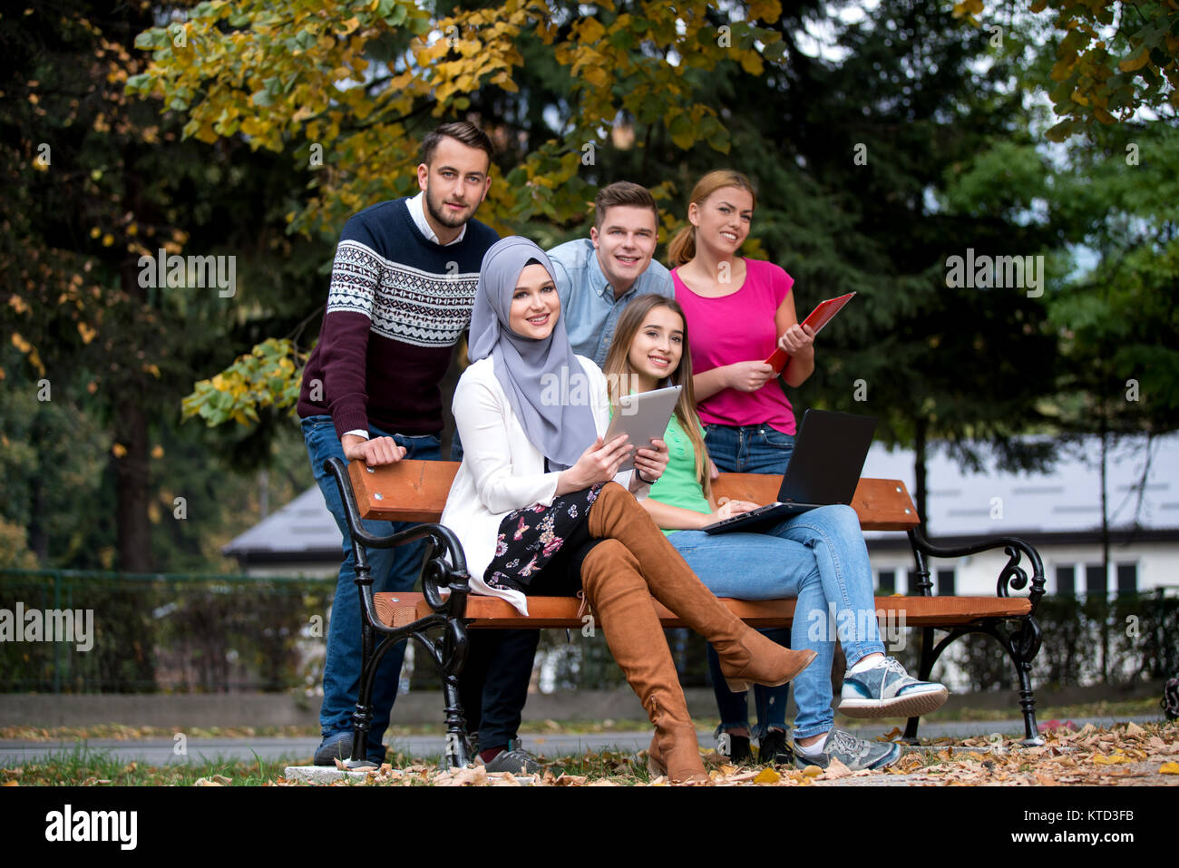 Gruppe von Jugendlichen mit Notebook und Tablet-PC auf einer Parkbank, Spass haben, Reden, heraus hängen Stockfoto