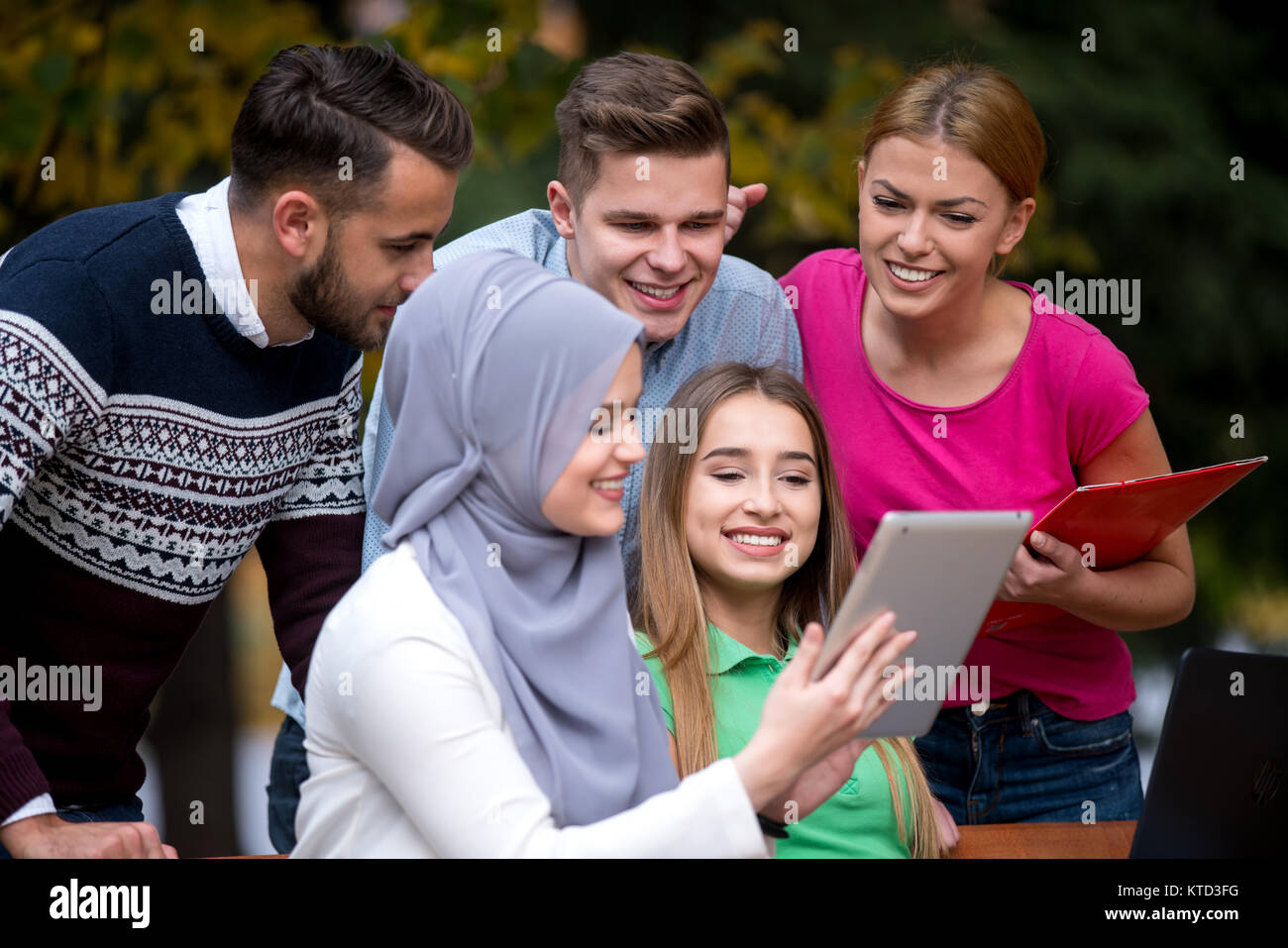 Gruppe von Jugendlichen mit Notebook und Tablet-PC auf einer Parkbank, Spass haben, Reden, heraus hängen Stockfoto