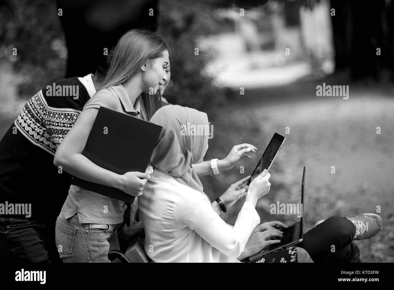 Gruppe von Jugendlichen mit Notebook und Tablet-PC auf einer Parkbank, Spass haben, Reden, heraus hängen Stockfoto