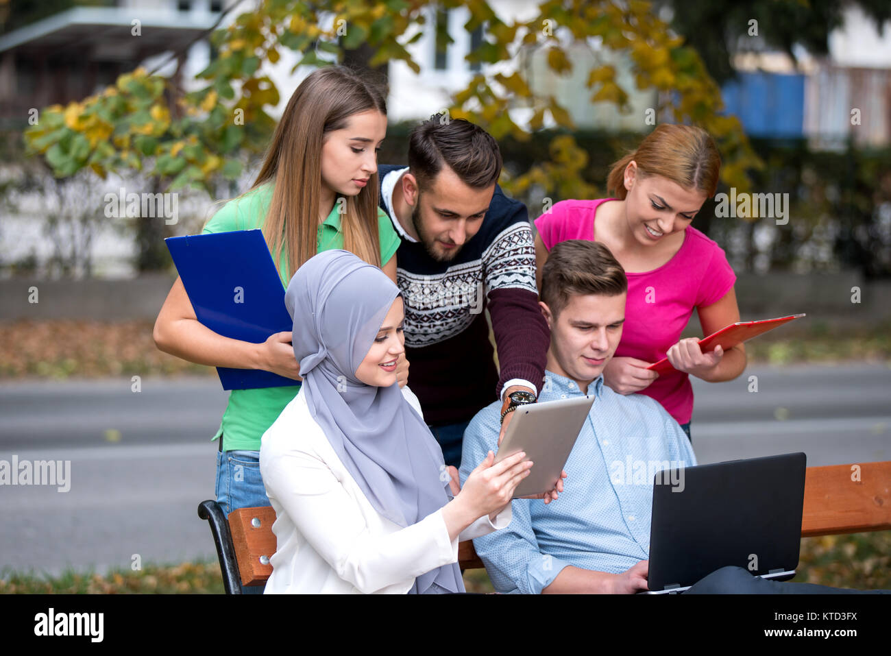 Gruppe von Jugendlichen mit Notebook und Tablet-PC auf einer Parkbank, Spass haben, Reden, heraus hängen Stockfoto