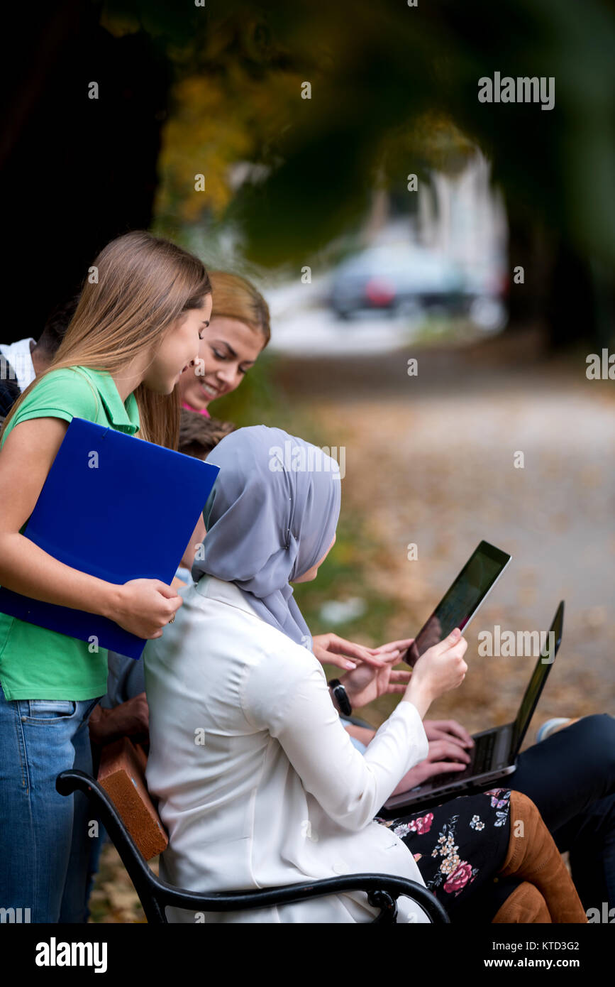 Gruppe von Jugendlichen mit Notebook und Tablet-PC auf einer Parkbank, Spass haben, Reden, heraus hängen Stockfoto