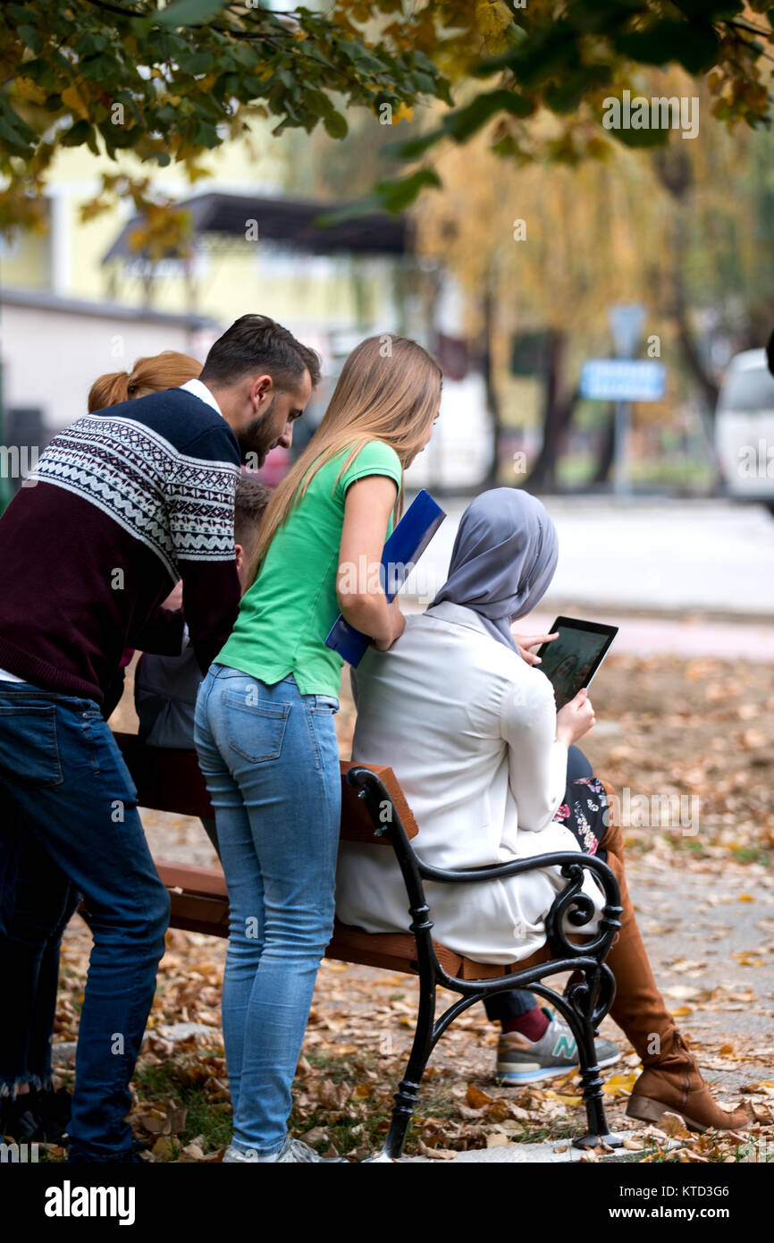 Gruppe von Jugendlichen mit Notebook und Tablet-PC auf einer Parkbank, Spass haben, Reden, heraus hängen Stockfoto