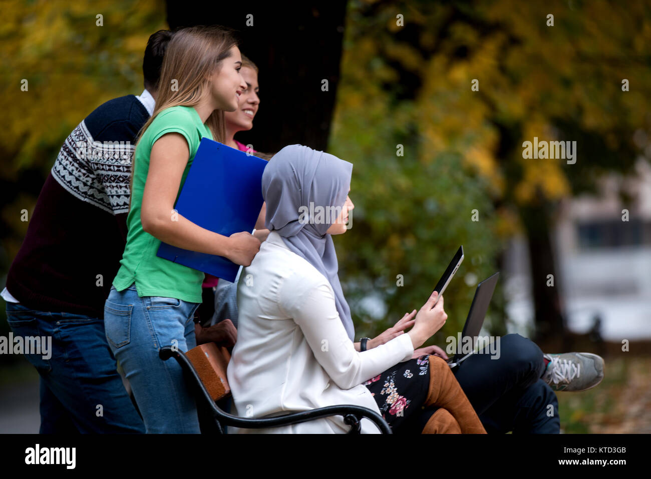 Gruppe von Jugendlichen mit Notebook und Tablet-PC auf einer Parkbank, Spass haben, Reden, heraus hängen Stockfoto