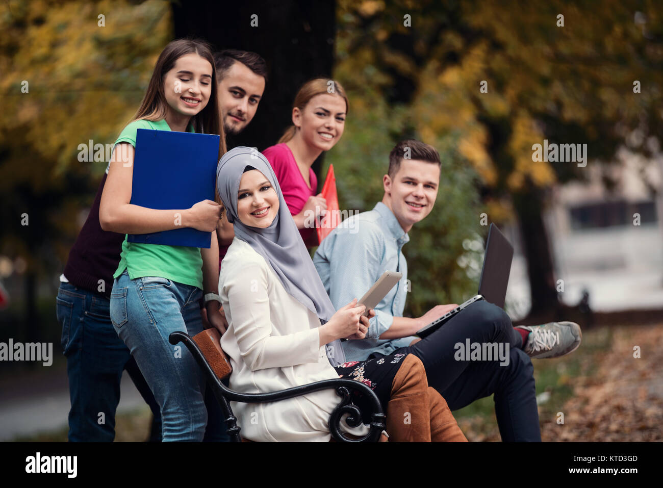 Gruppe von Jugendlichen mit Notebook und Tablet-PC auf einer Parkbank, Spass haben, Reden, heraus hängen Stockfoto