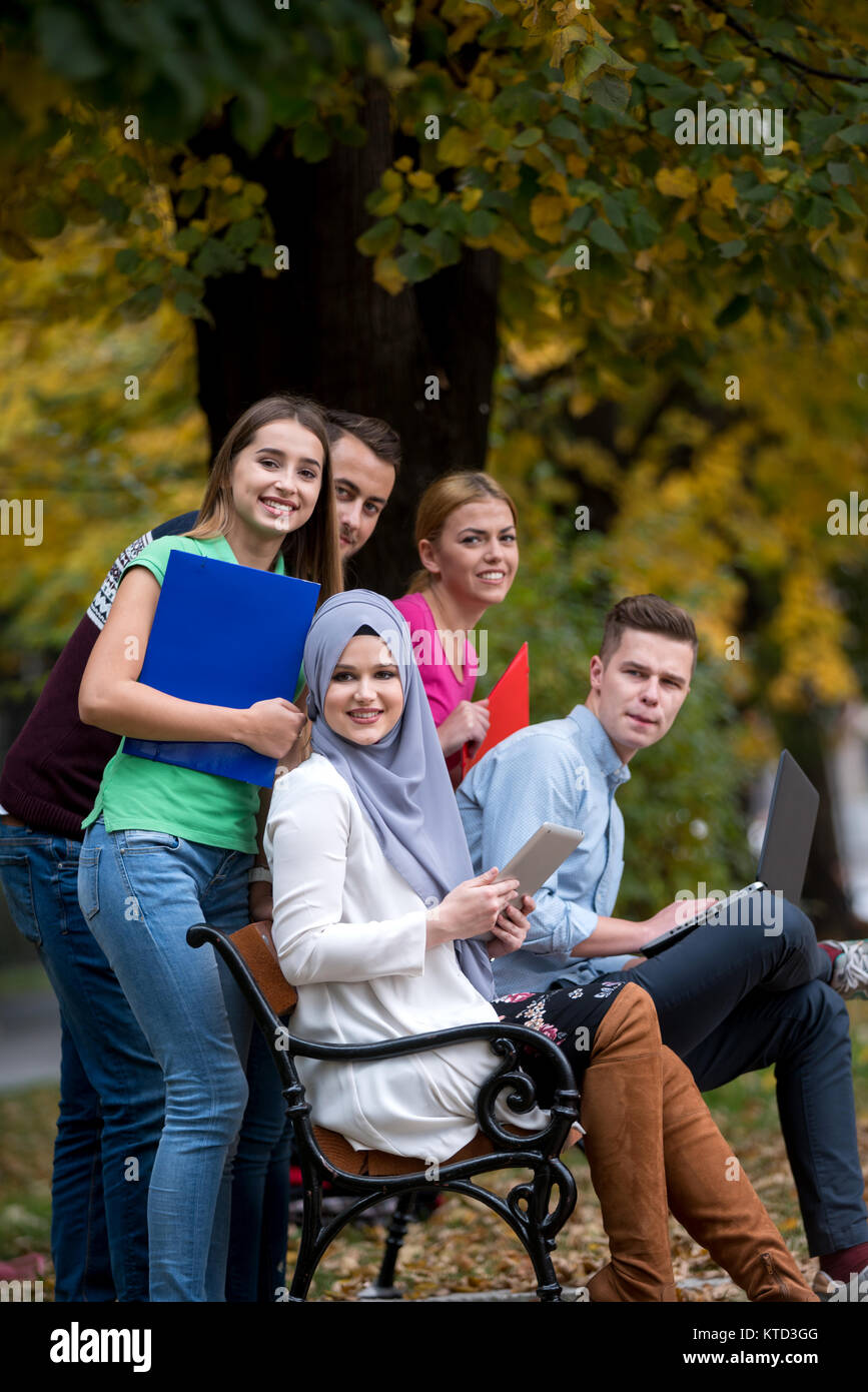 Gruppe von Jugendlichen mit Notebook und Tablet-PC auf einer Parkbank, Spass haben, Reden, heraus hängen Stockfoto
