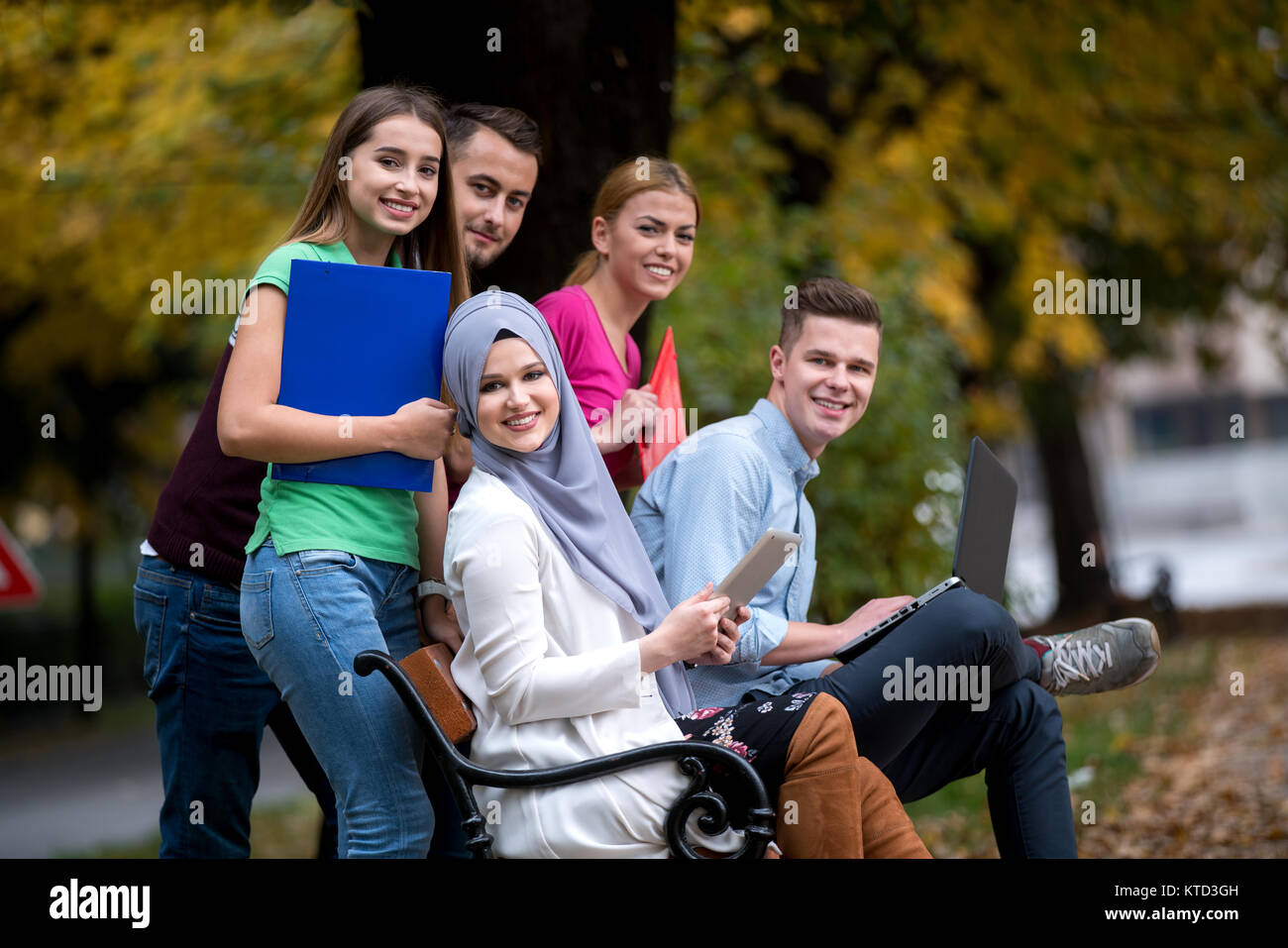 Gruppe von Jugendlichen mit Notebook und Tablet-PC auf einer Parkbank, Spass haben, Reden, heraus hängen Stockfoto