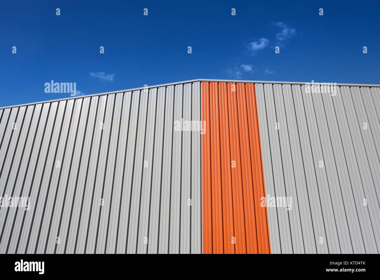 Ein grafischer orangefarbener Streifen auf einem modernen Gebäudedetail dagegen Ein blauer Himmel - geometrischer Minimalismus Stockfoto