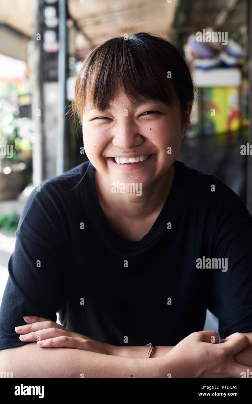 Attraktive junge asiatische Frau in die Kamera Lachen, die Arme verschränkt. Chiang Mai, Thailand. Stockfoto