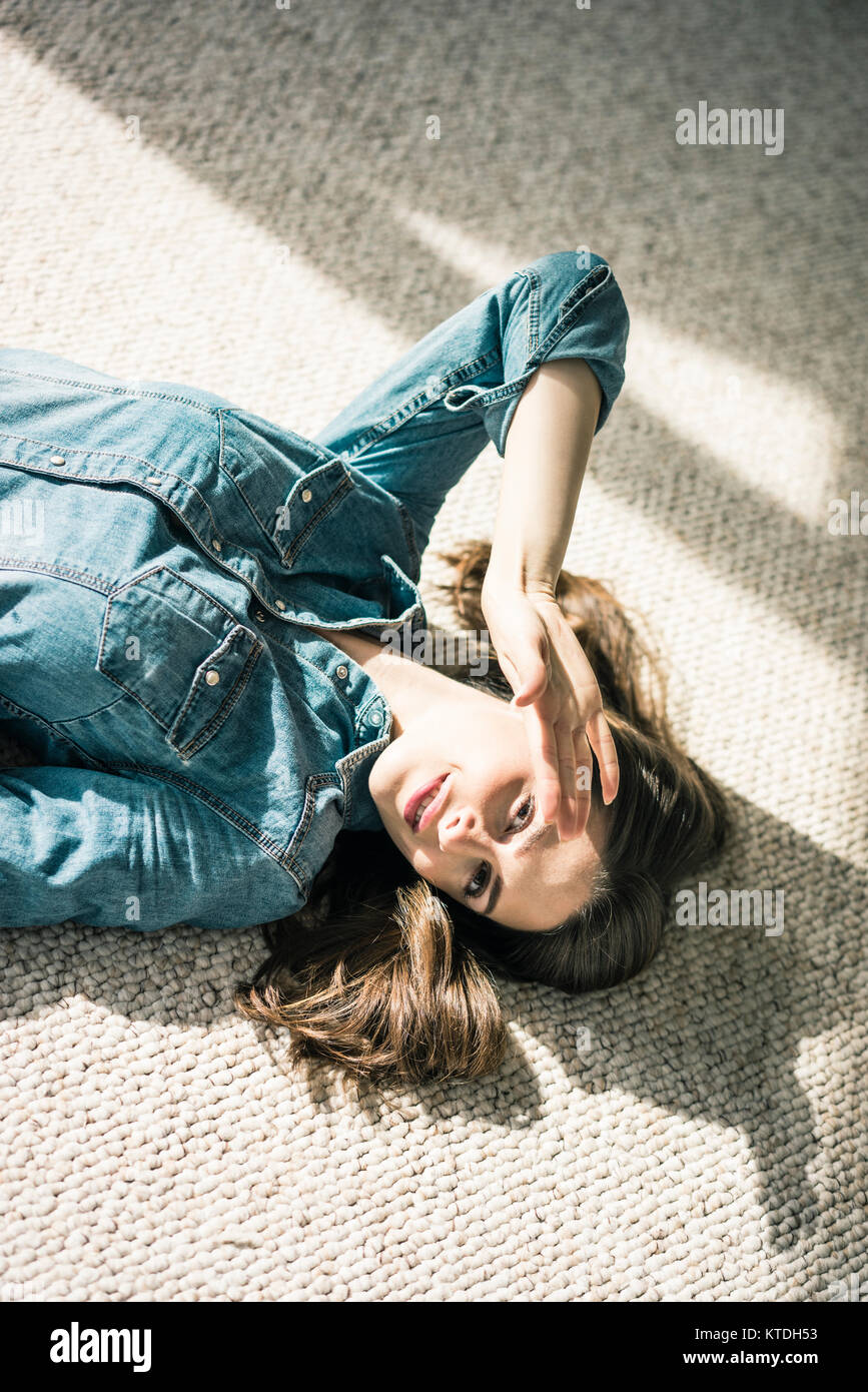 Porträt der jungen Frau liegend auf dem Teppich Sonnenlicht genießen. Stockfoto