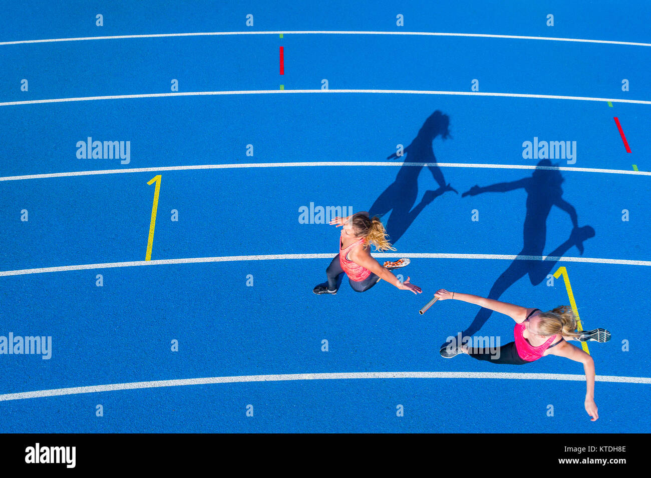 Blick von oben auf die zwei weiblichen Läufern vorbei an den Staffelstab auf der Tartanbahn Stockfoto