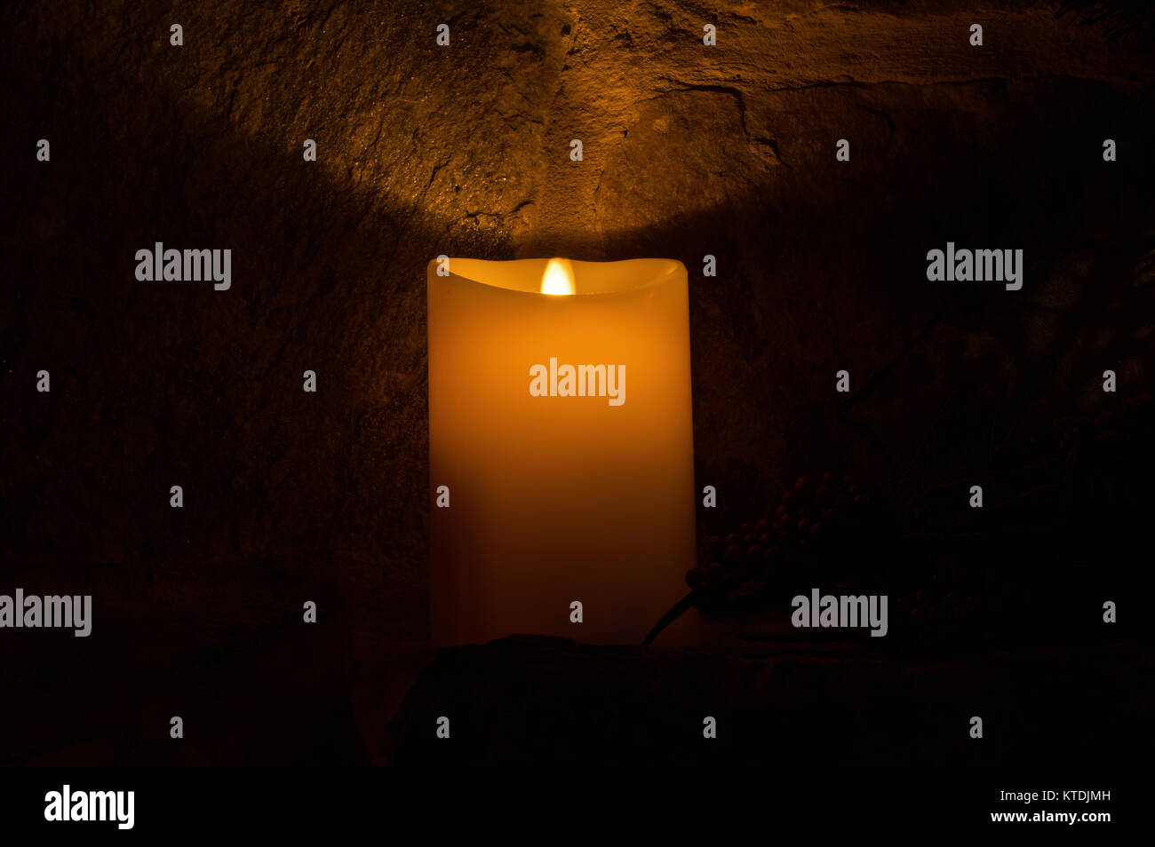 Kerze auf dem kaminsims von einem Kamin aus Stein in einem abgedunkelten Raum. Stockfoto