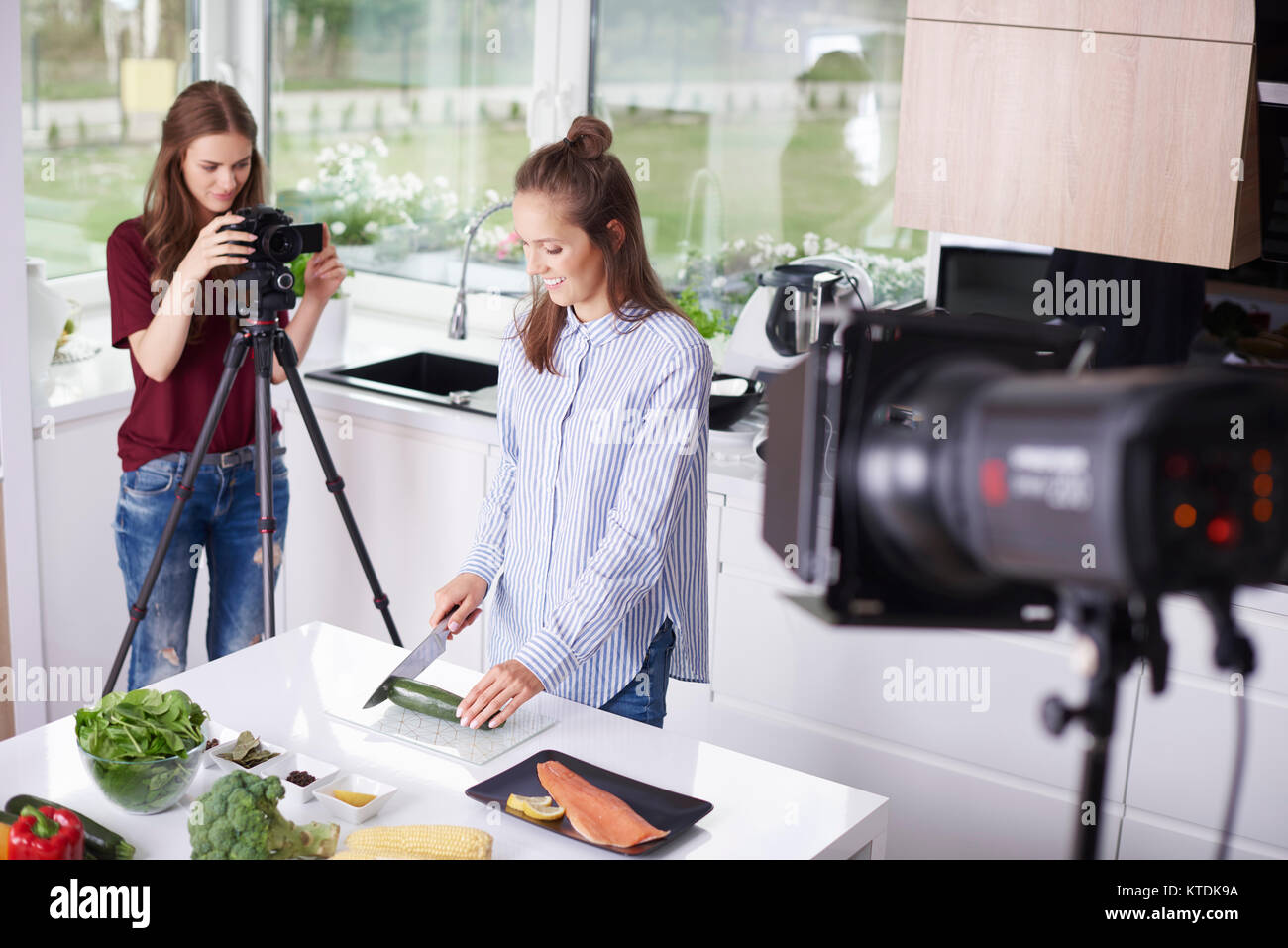 Frau Aufnahme ihrer Freundin beim Hacken eine Zucchini Stockfoto