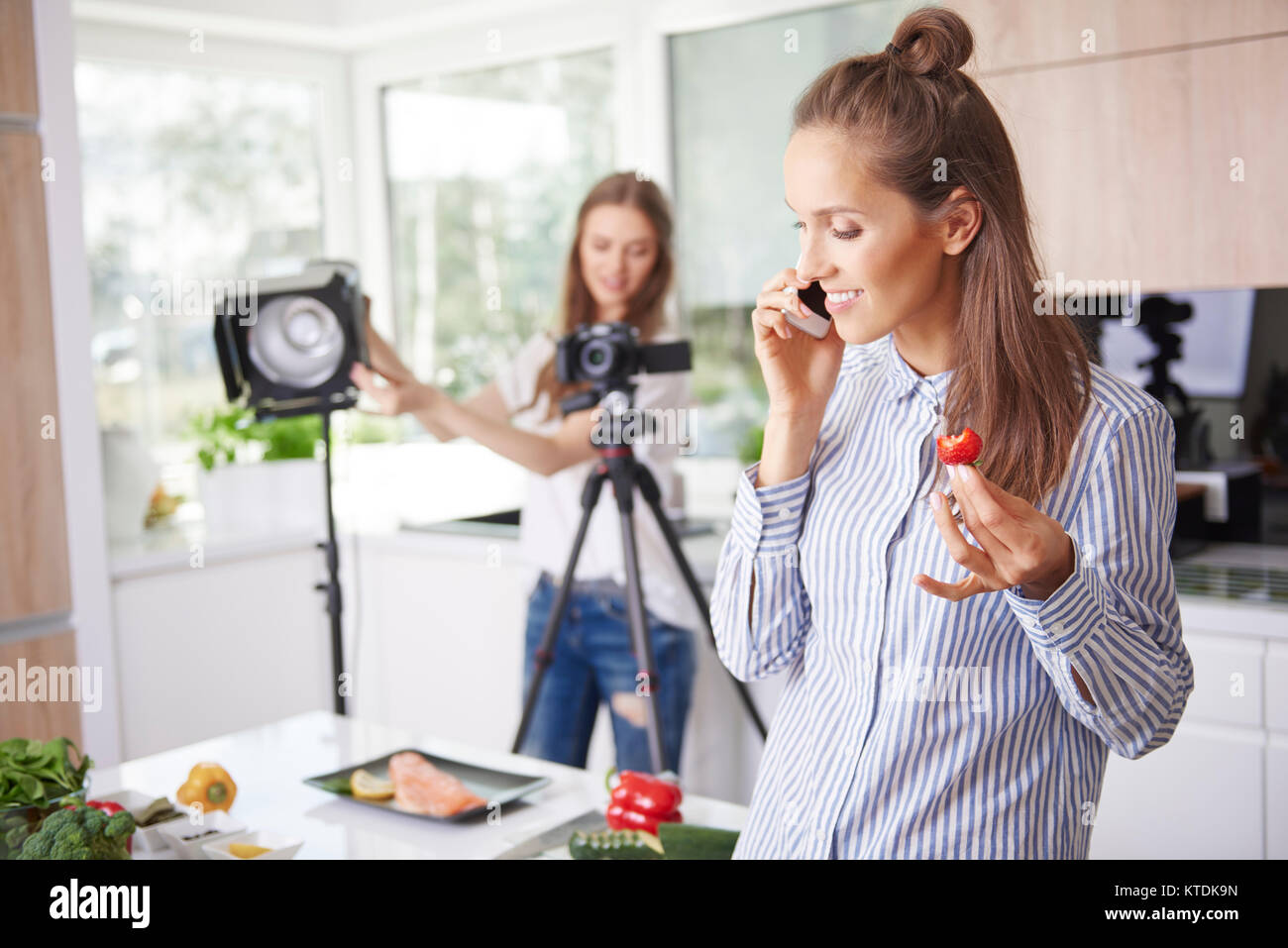 Frau am Telefon zu sprechen und Erdbeeren essen Stockfoto