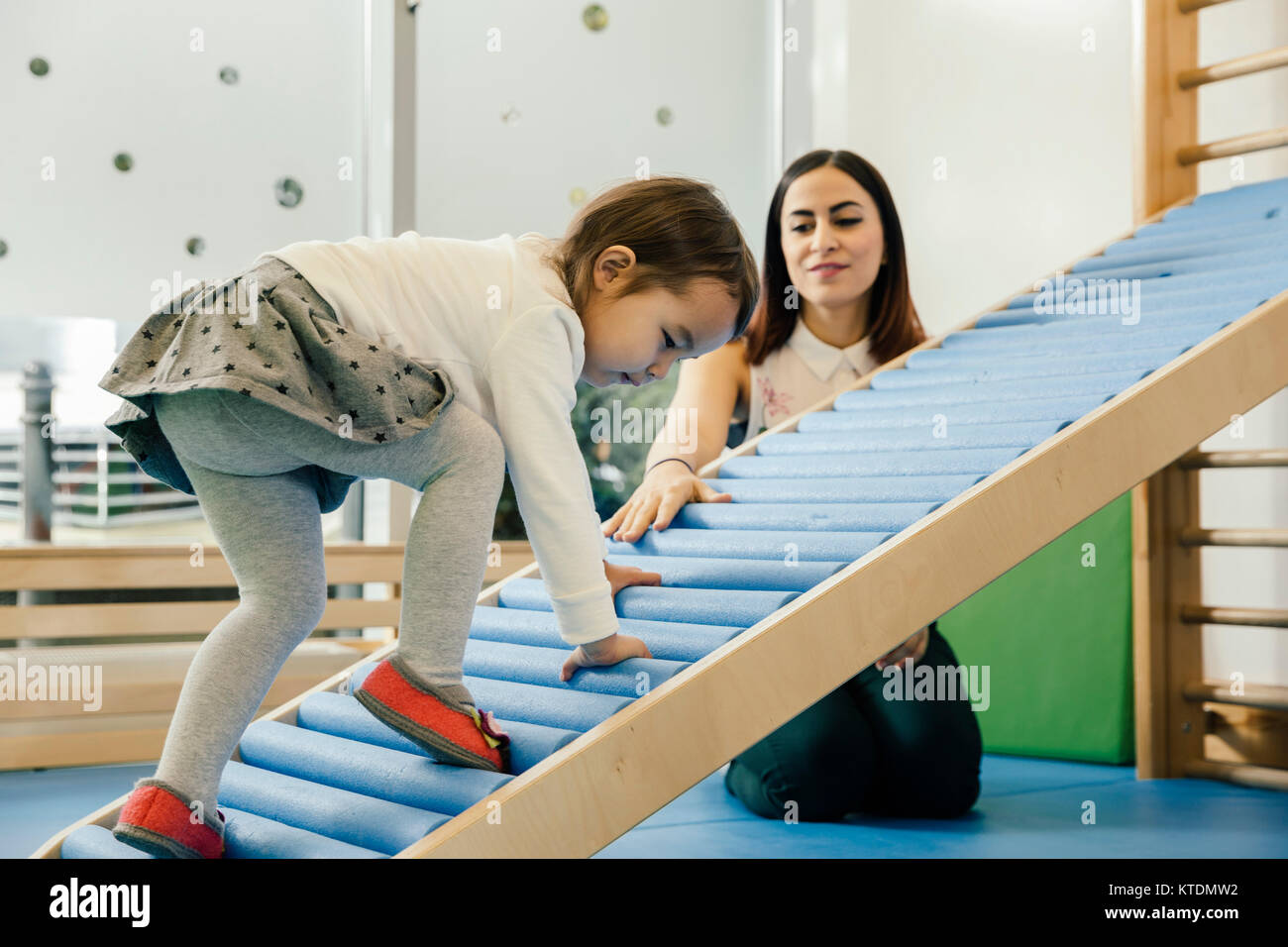 Pre-school Lehrer beobachten, kleine Mädchen zu Fuß nach oben Stockfoto