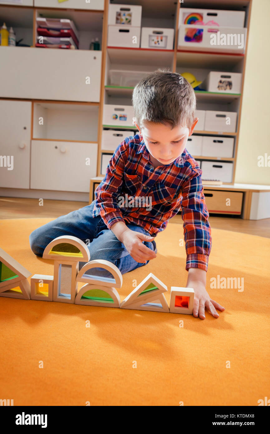 Junge Futter bis Holzspielzeug Formen auf dem Teppich im Kindergarten Stockfoto