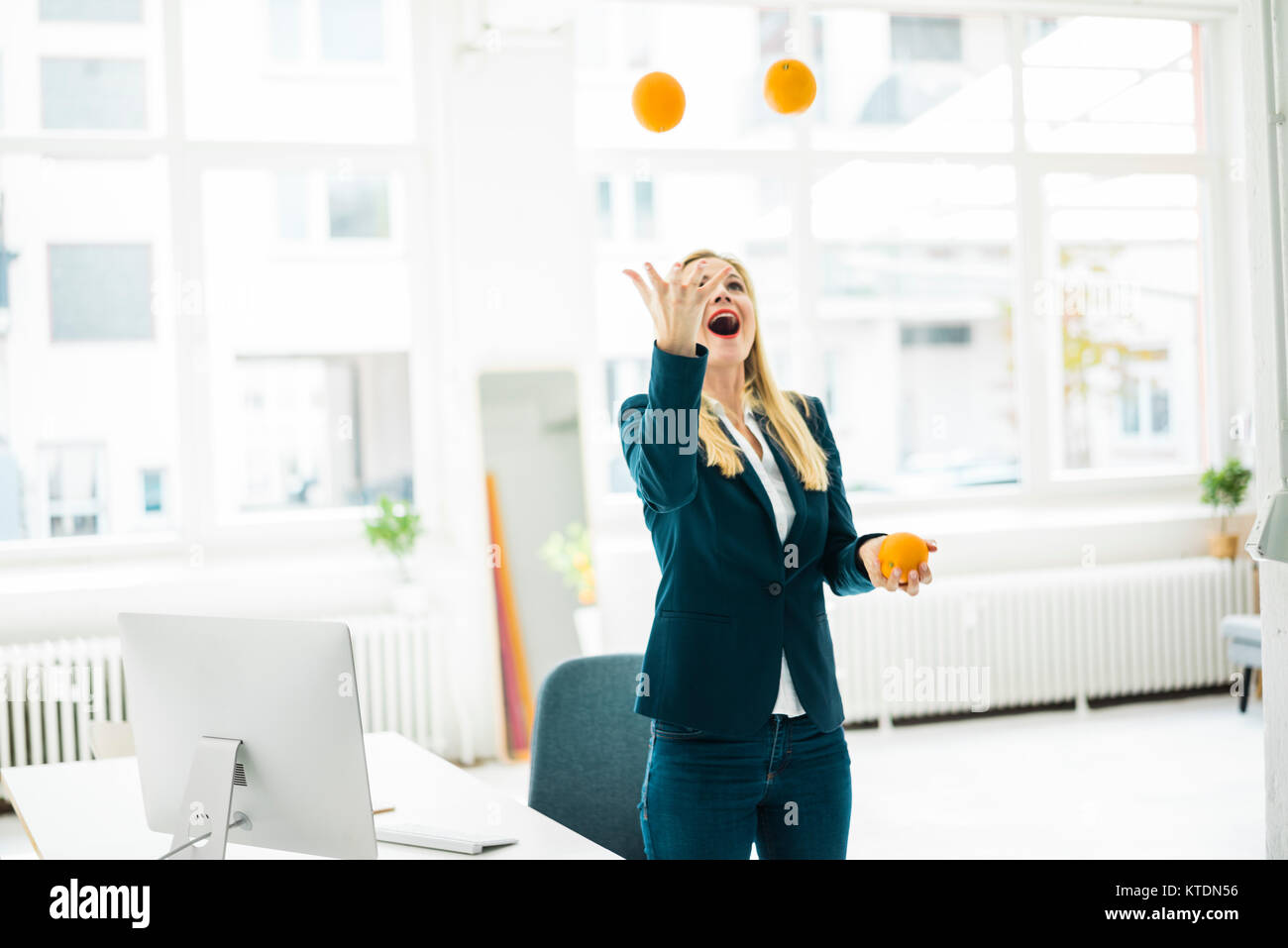 Sorglos Geschäftsfrau jonglieren mit Orangen in Office Stockfoto