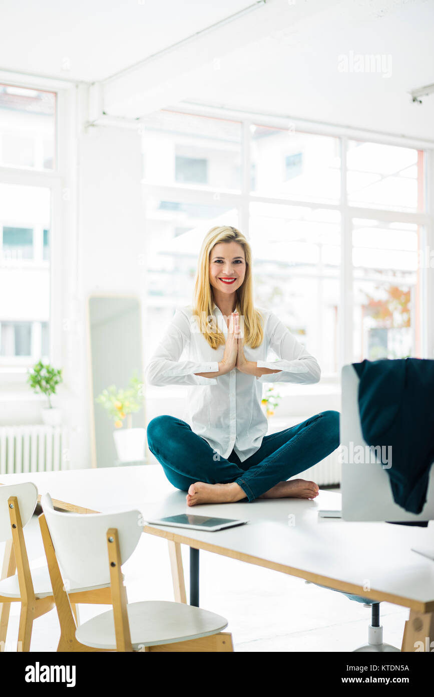 Lächeln, Geschäftsfrau, sitzen am Schreibtisch im Büro Yoga Stockfoto