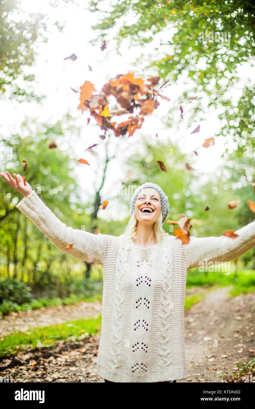 Glückliche Frau im Wald im Herbst werfen Blätter in der Luft Stockfoto
