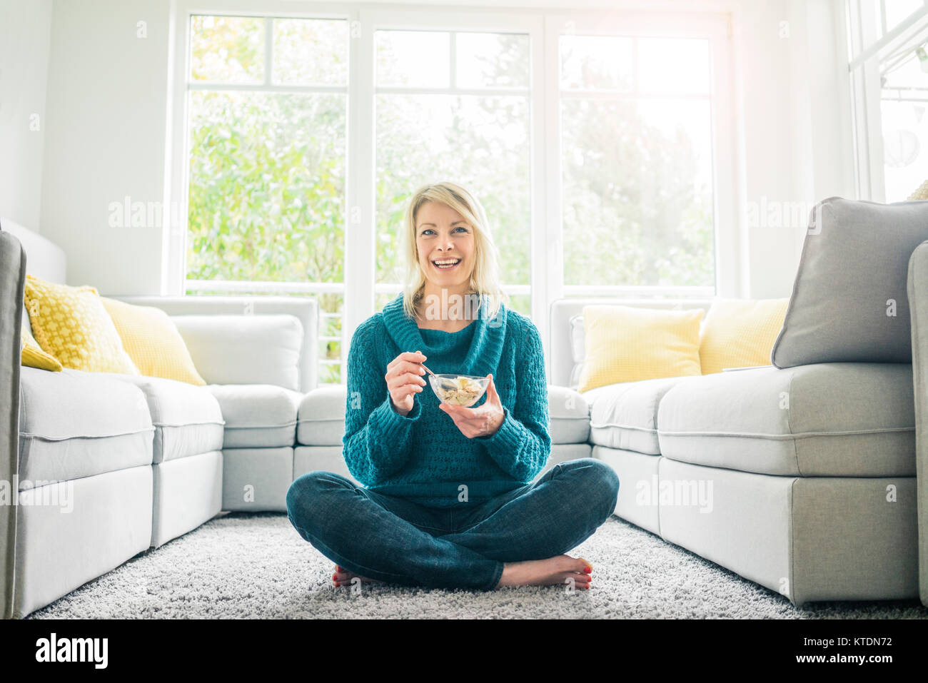 Portrait von Frau isst Müsli im Wohnzimmer Stockfoto