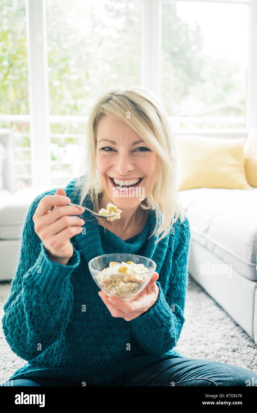 Portrait von Frau essen Obst Müsli im Wohnzimmer Stockfoto