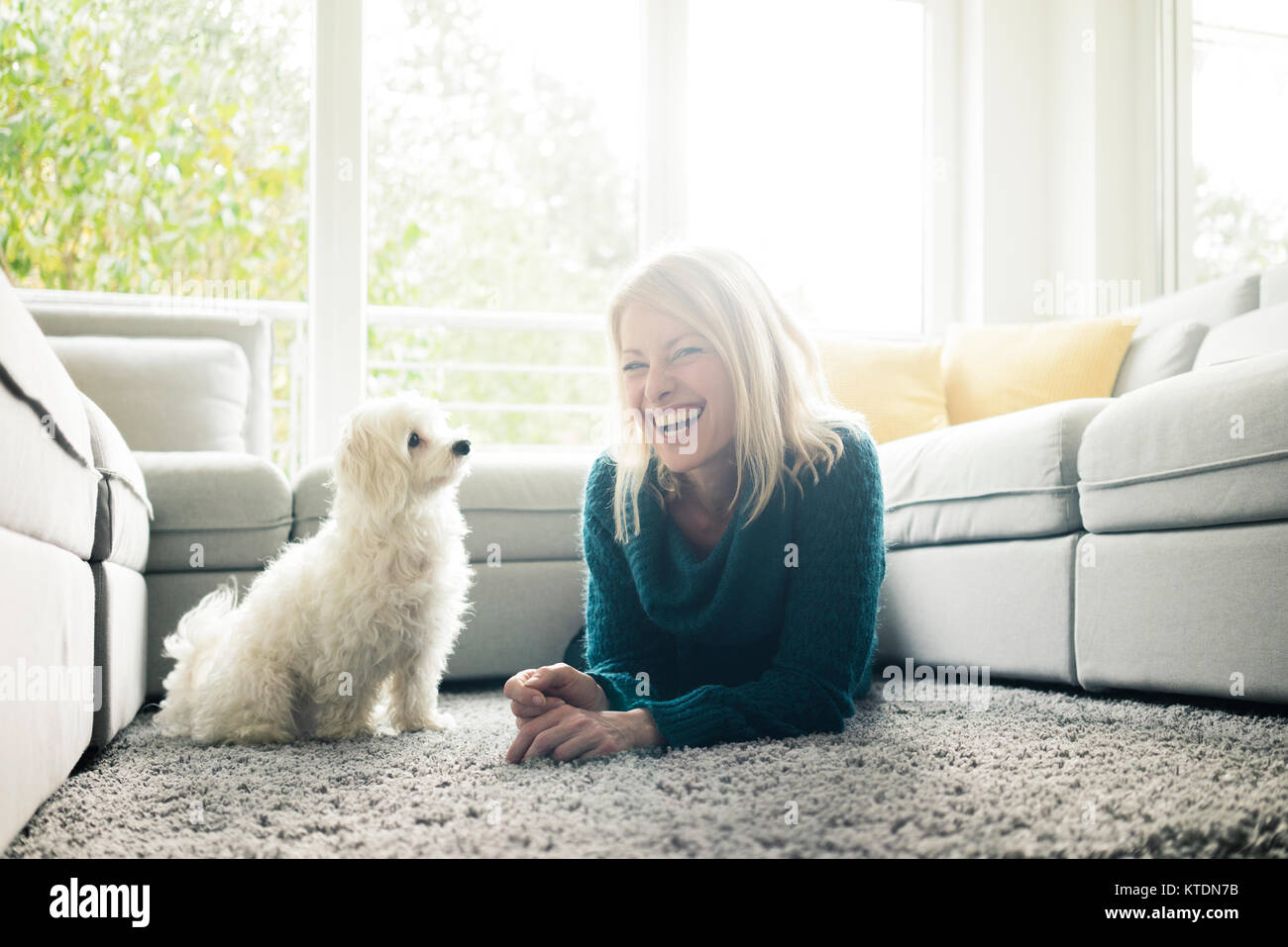 Glückliche Frau mit Hund im Wohnzimmer Stockfoto