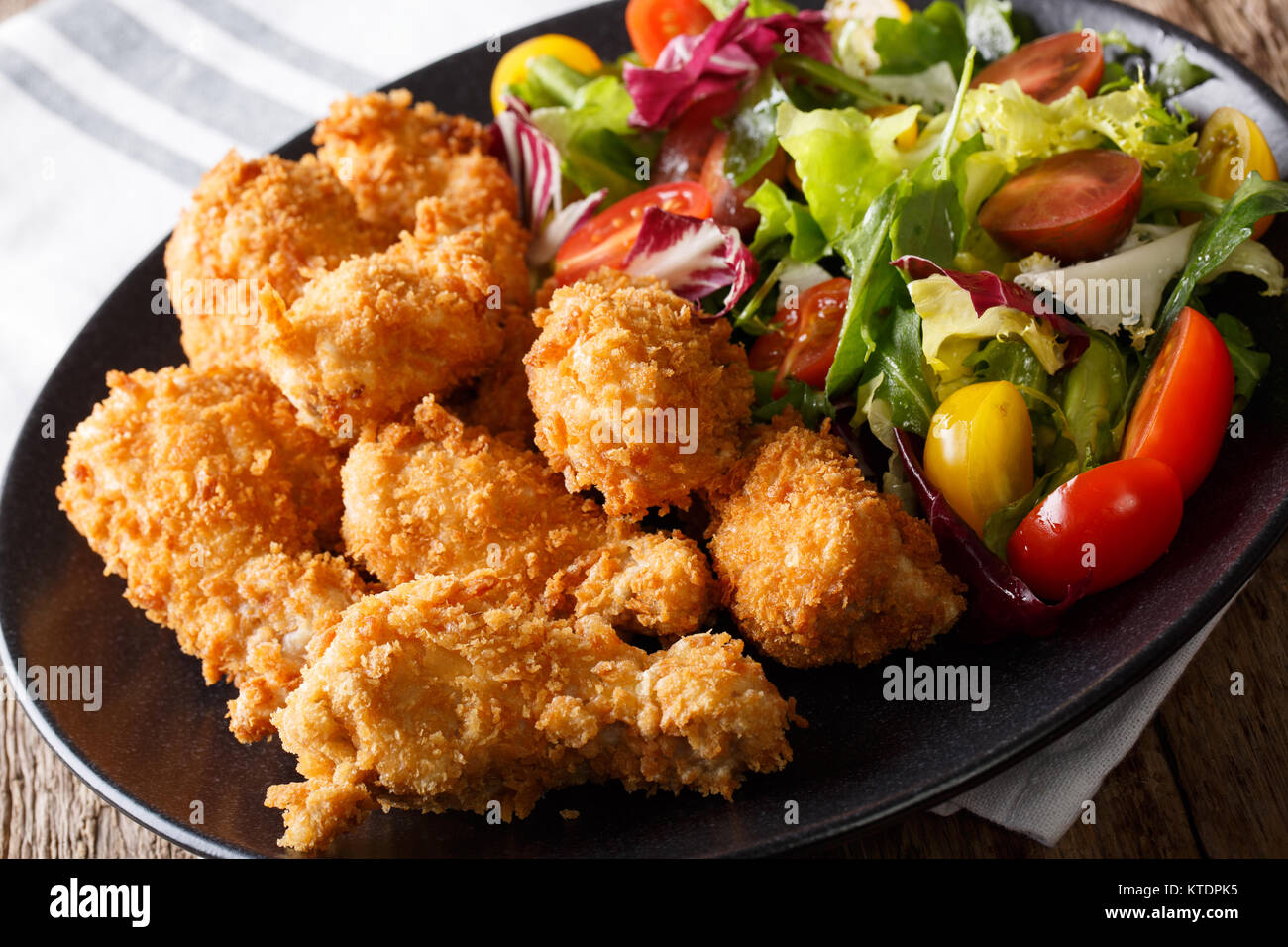 Würzige frittierte Hähnchenflügel in Semmelbrösel und frisches Gemüse Salat close-up auf einem Teller. Horizontale Stockfoto