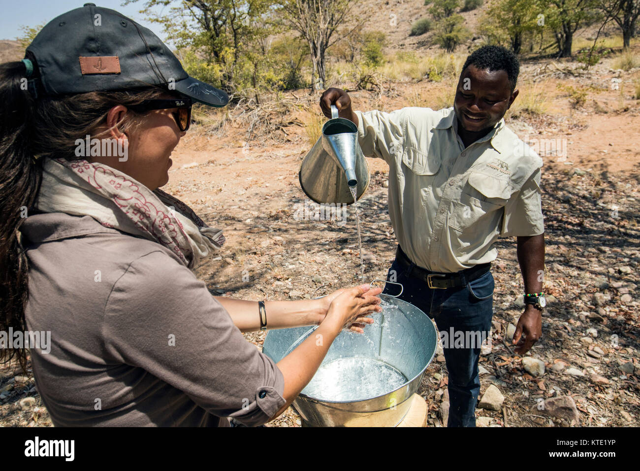 Frau waschen ihre Hände in Zinn Becken - Huab unter Leinwand, Damaraland, Namibia, Afrika Stockfoto