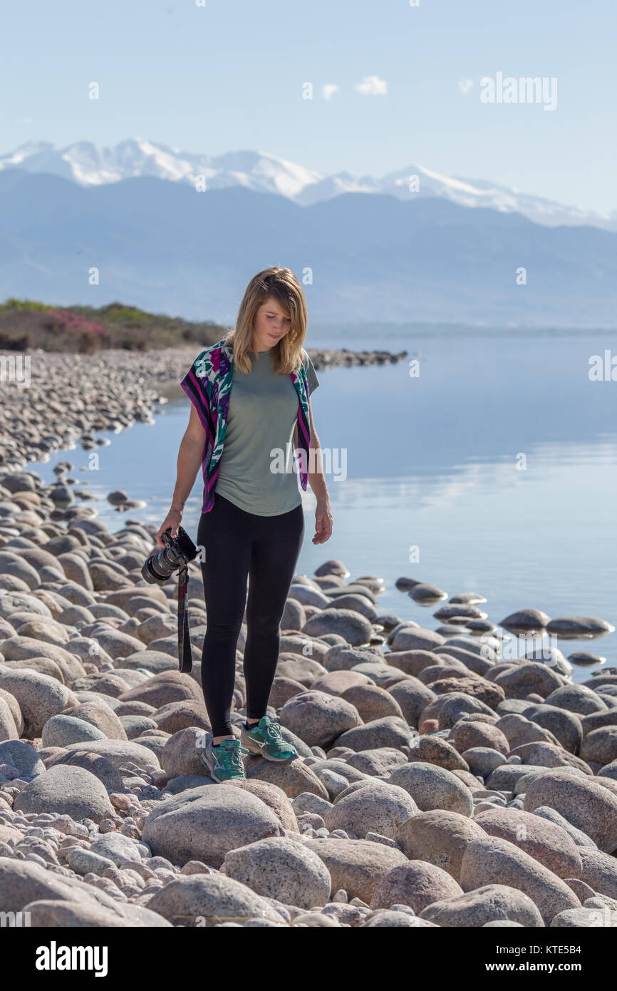 Ein weibliches Modell am Südufer von Issyk-Kol in Kirgisistan, im Hintergrund spiegeln sich die Berge des Nordufers. Stockfoto