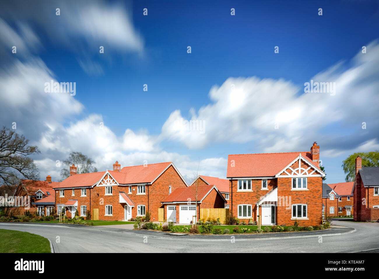 Neue Wohnsiedlung mit Wolken verschwommen gegen den blauen Himmel. Großbritannien Stockfoto